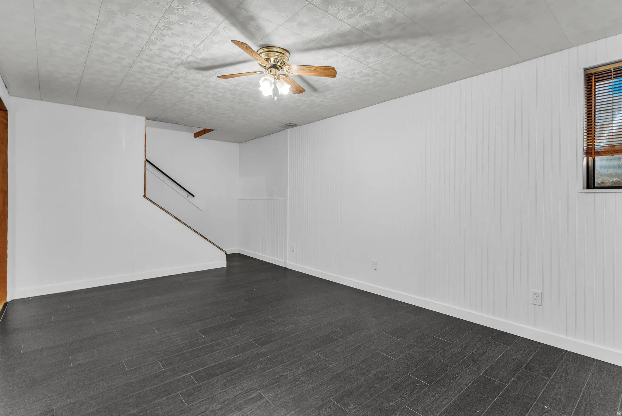 Empty room featuring a ceiling fan and dark wood-type flooring