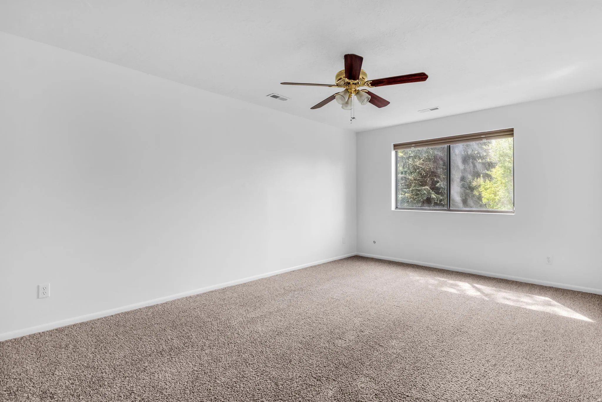 Carpeted spare room with baseboards and a ceiling fan