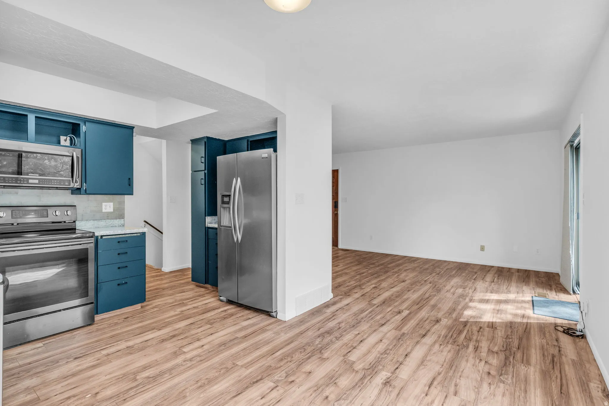 Kitchen featuring blue cabinets, stainless steel appliances, light wood finished floors, and open shelves