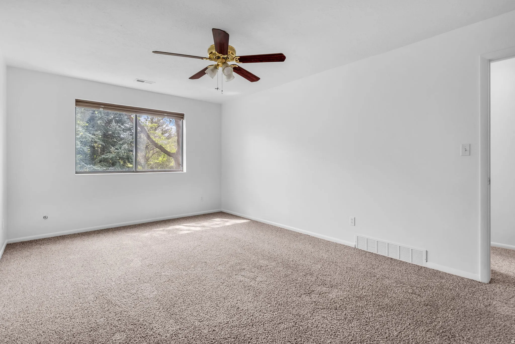 Empty room featuring carpet flooring and a ceiling fan