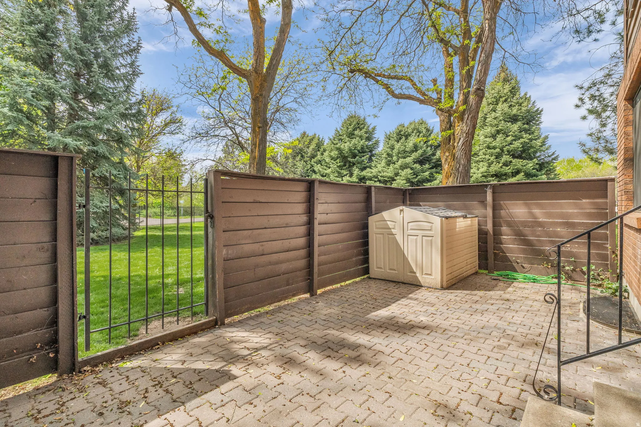 Fenced patio featuring a patio area, a storage unit, and a gate