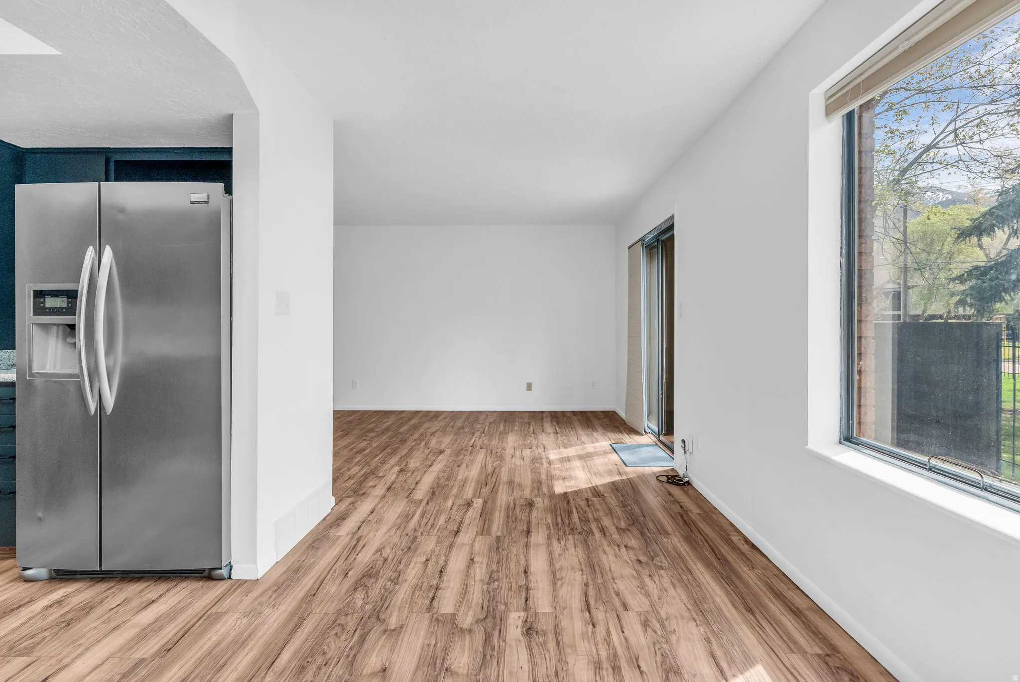 Kitchen featuring stainless steel refrigerator with ice dispenser and light wood-style floors