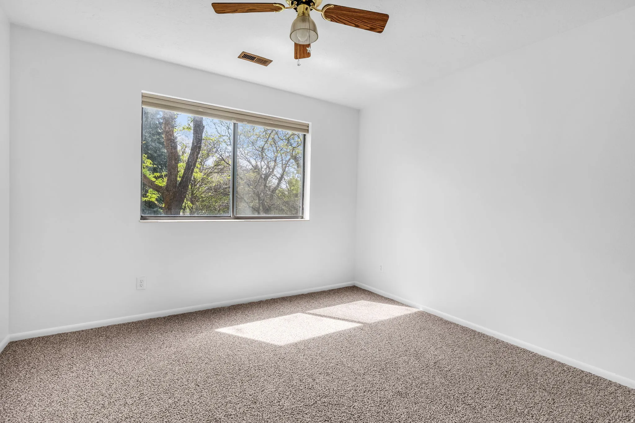 Carpeted spare room with ceiling fan and baseboards