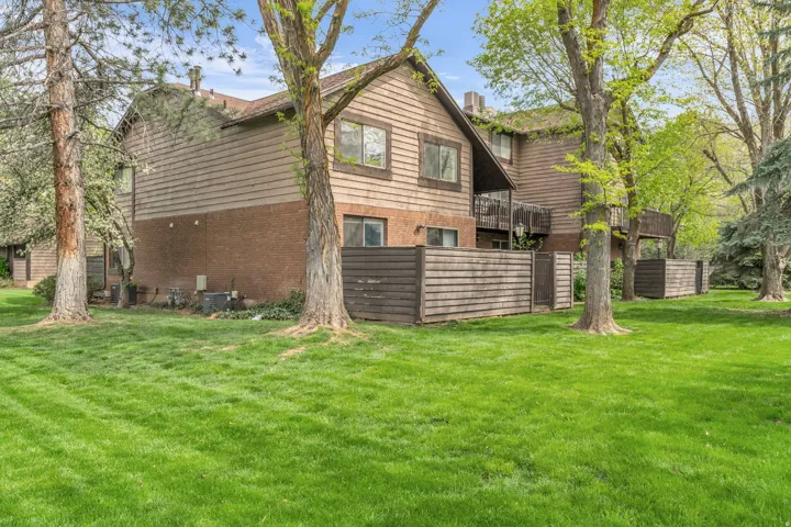 Rear view of property with a yard, brick siding, a balcony, and a chimney