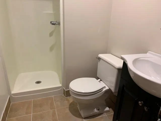 Full bathroom with a shower stall, vanity, and light tile patterned floors