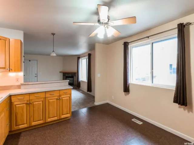 Kitchen featuring dark floors, pendant lighting, a glass covered fireplace, and light countertops