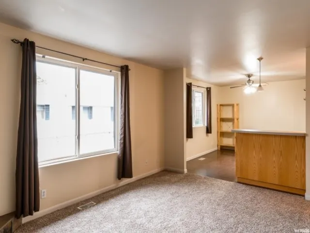 Unfurnished living room featuring dark carpet and ceiling fan