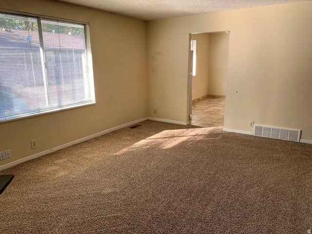 Unfurnished room featuring a textured ceiling and carpet