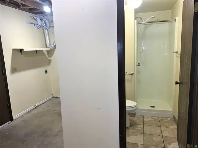 Full bath featuring a stall shower and concrete floors