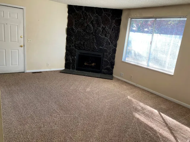 Unfurnished living room with carpet, a fireplace, and a textured ceiling