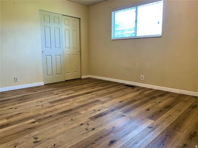Unfurnished bedroom featuring a closet and dark wood-style floors