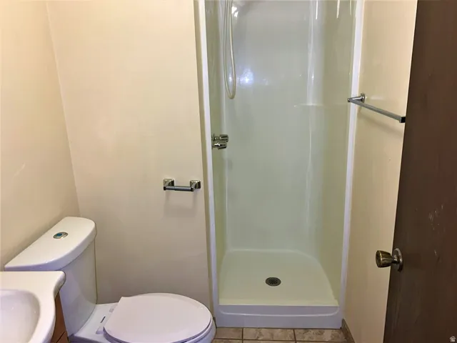 Full bath with a stall shower, vanity, and tile patterned flooring