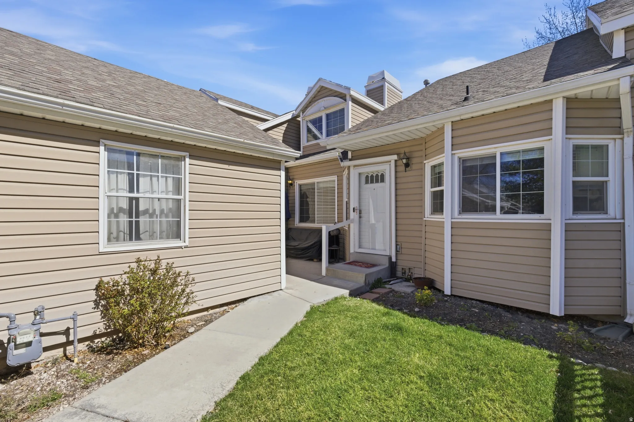Property entrance with a lawn and a shingled roof