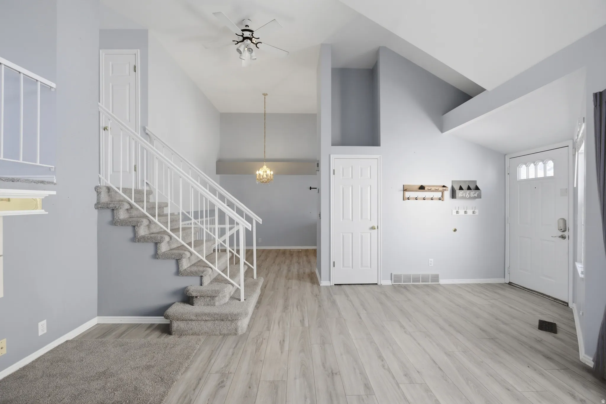 Foyer featuring light wood-style flooring, suspended lighting, a ceiling fan, and a high ceiling