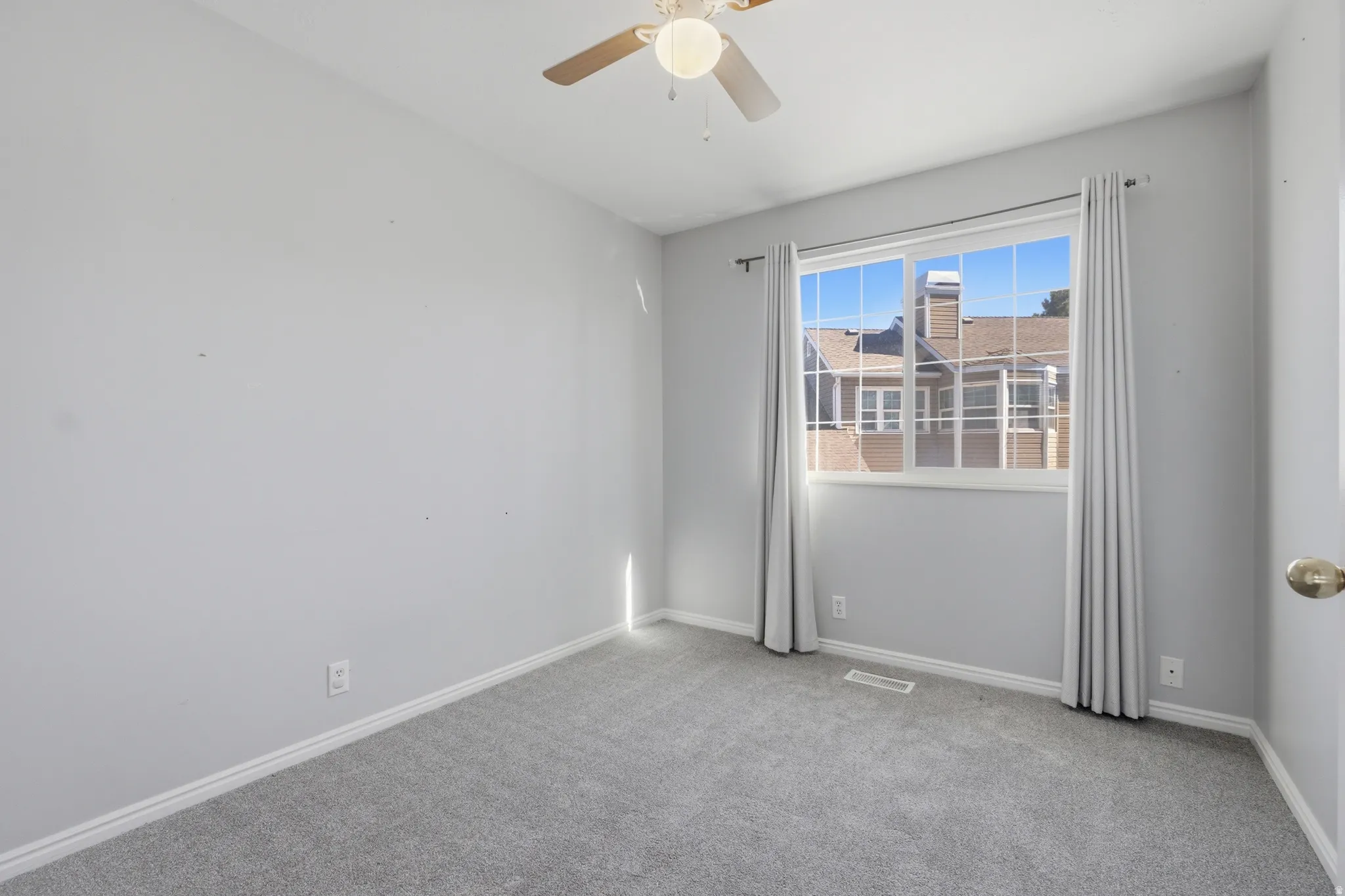 Unfurnished room featuring light colored carpet and a ceiling fan
