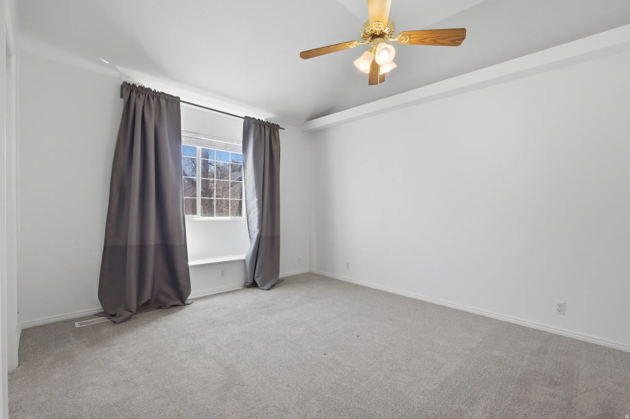 Spare room with light colored carpet, ceiling fan, and lofted ceiling