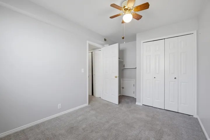 Unfurnished bedroom featuring light colored carpet, ceiling fan, and a closet