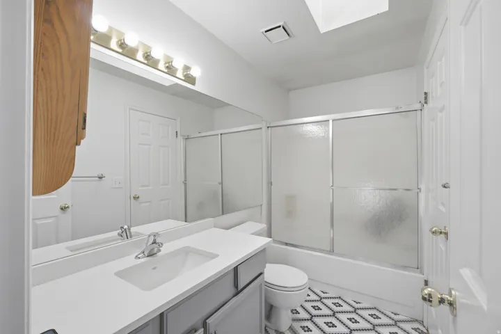 Full bath featuring vanity and combined bath / shower with glass door