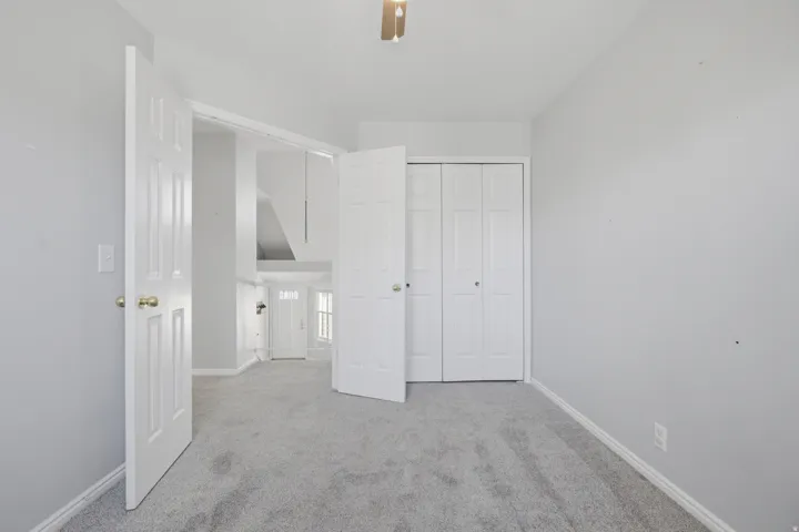 Unfurnished bedroom with light carpet, a closet, and ceiling fan