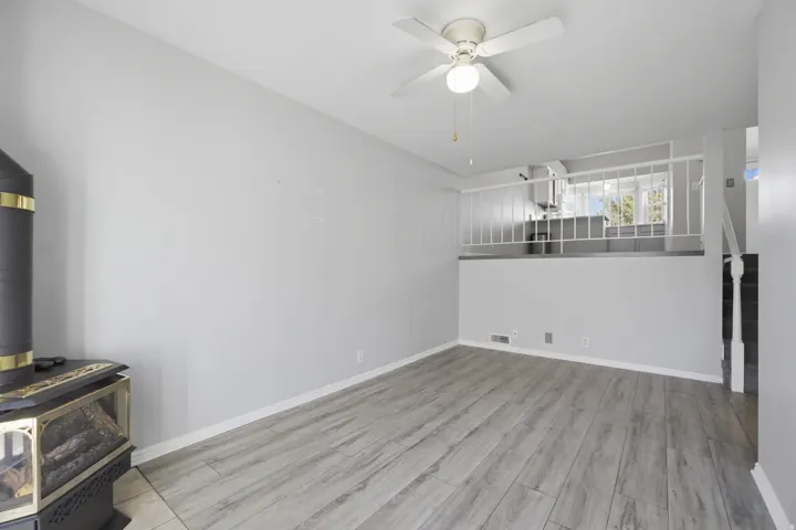 Unfurnished living room with ceiling fan, light wood finished floors, and a wood stove
