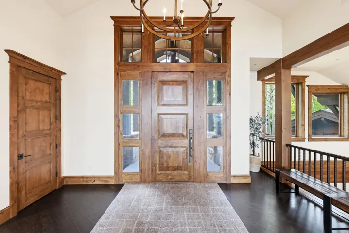 Grand entryway featuring a paneled wood door with sidelights, transom windows, and a vaulted ceiling