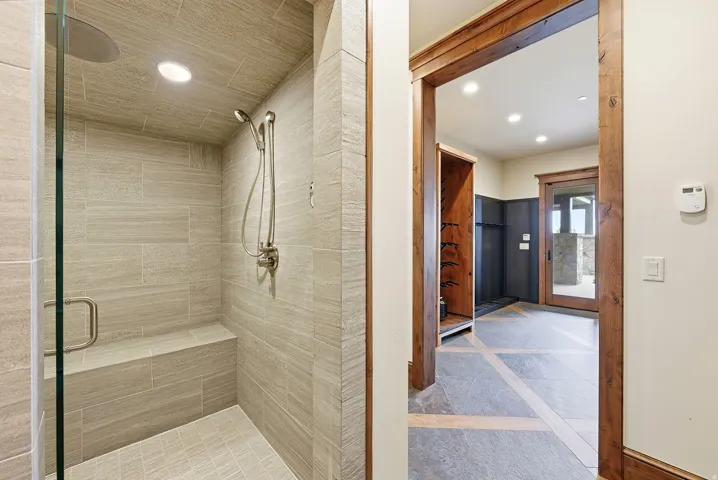 Walk-in shower with full tile surround, integrated bench, and rainfall showerhead with additional handheld spray
