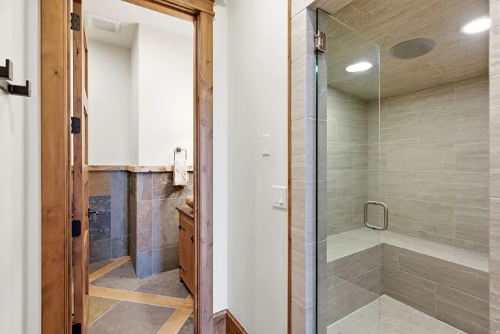 Glass-enclosed shower with a built-in bench, recessed lighting, and tile-finish walls