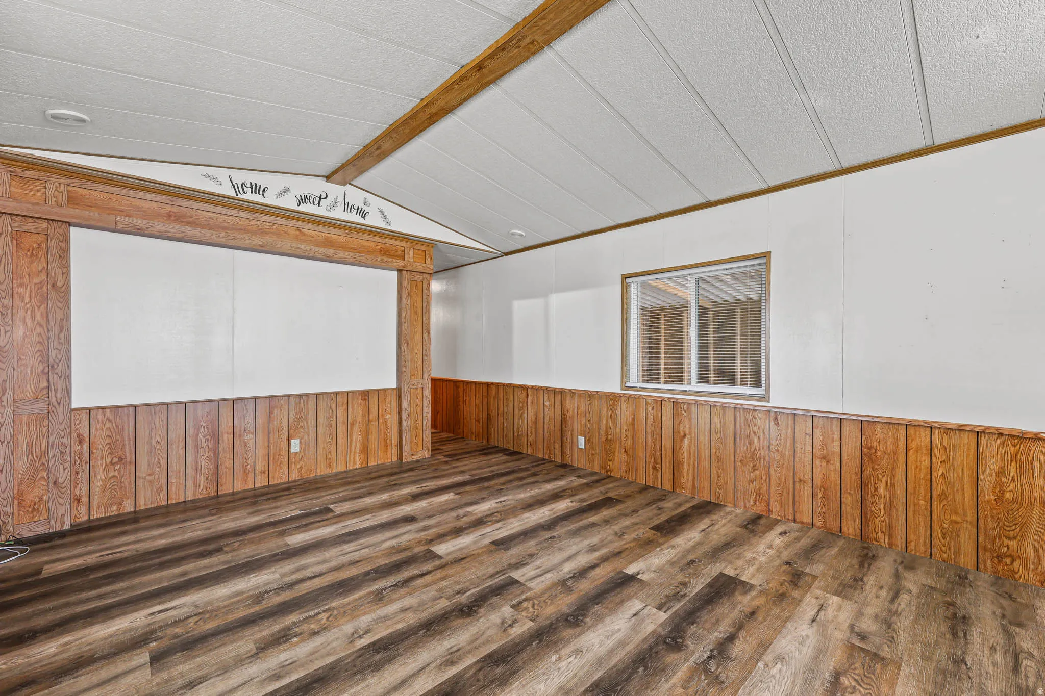Spare room with wood walls, dark wood-style floors, and wainscoting