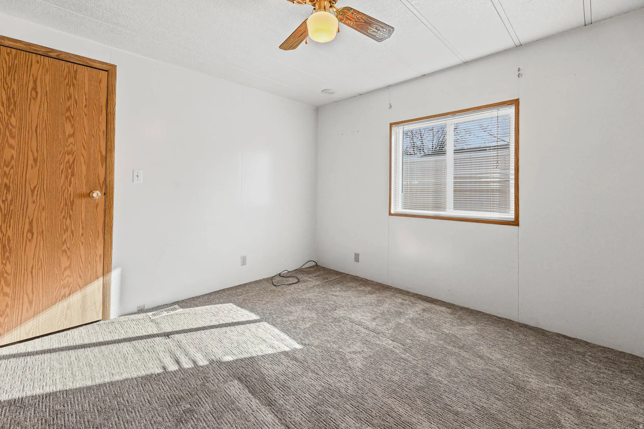 Empty room with carpet floors, a textured ceiling, and ceiling fan