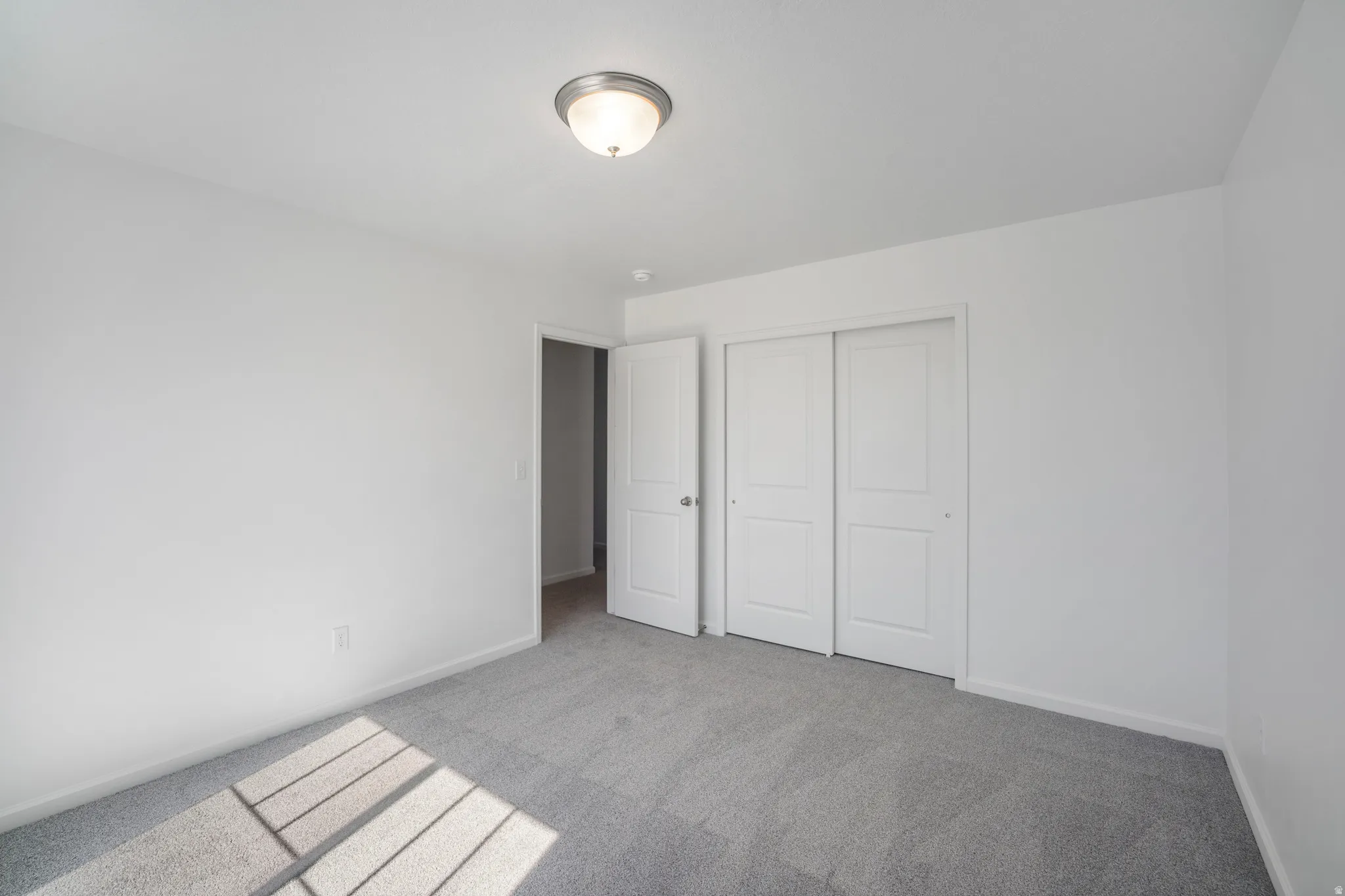 Unfurnished bedroom with light carpet and a closet