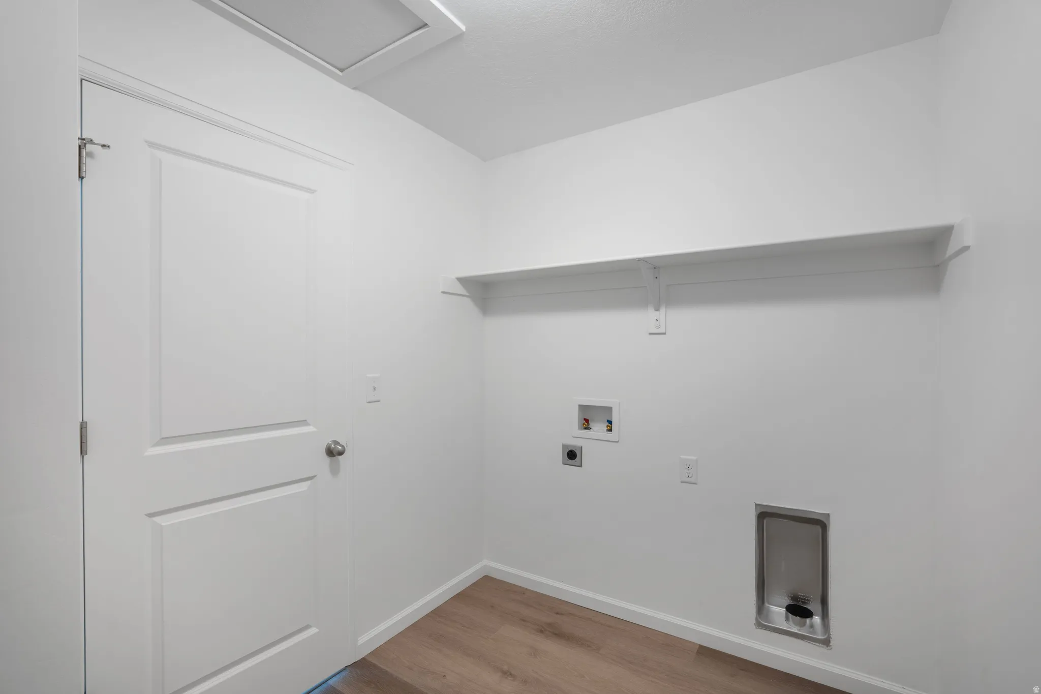 Laundry area with light wood-style floors, washer hookup, and electric dryer hookup