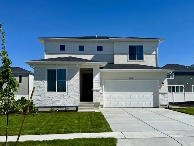 View of front of house featuring stone siding, driveway, a front lawn, and a garage