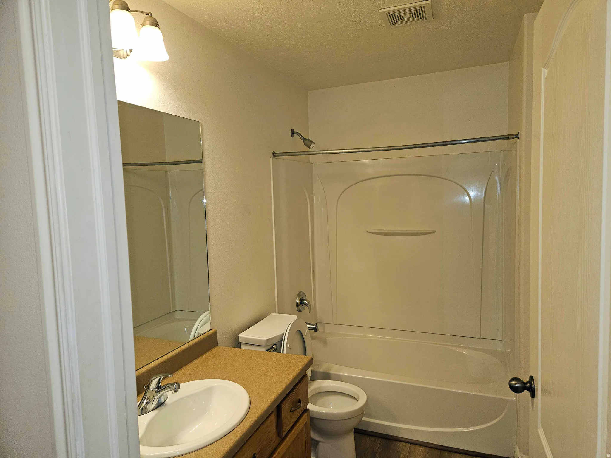 Full bathroom featuring vanity, bathing tub / shower combination, a textured ceiling, and wood finished floors