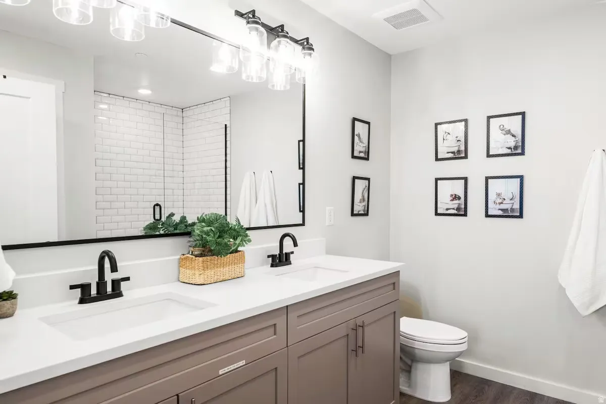 Bathroom with double vanity, a shower stall, and dark wood-style flooring