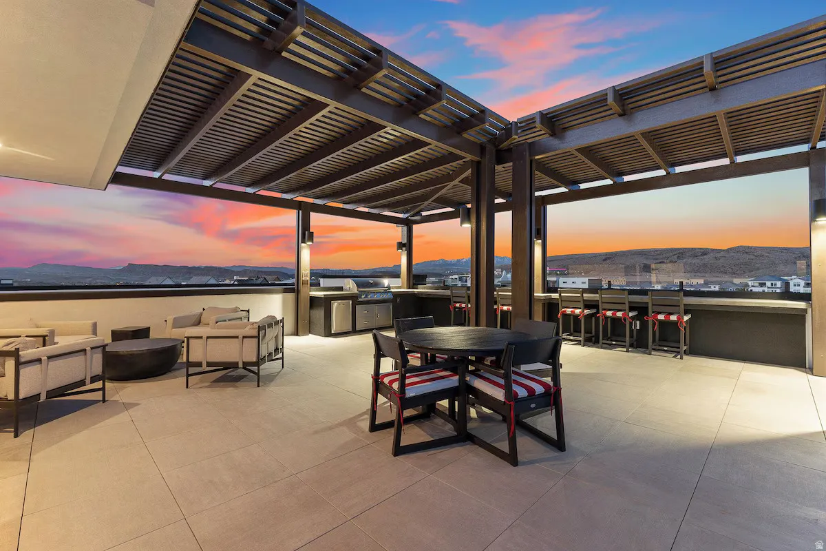 Patio terrace at dusk featuring a patio, outdoor dining area, a mountain view, a grill, and an outdoor living space