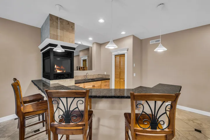 Kitchen with light tile patterned floors, a breakfast bar, hanging light fixtures, recessed lighting, and dark stone counters