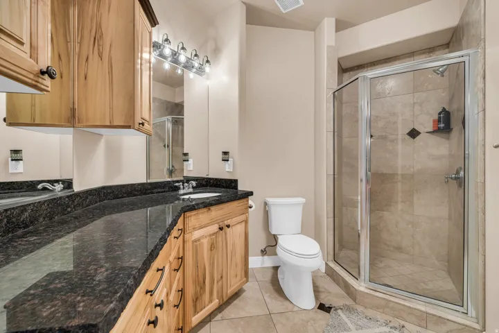 Full bath featuring a shower stall, vanity, and light tile patterned floors