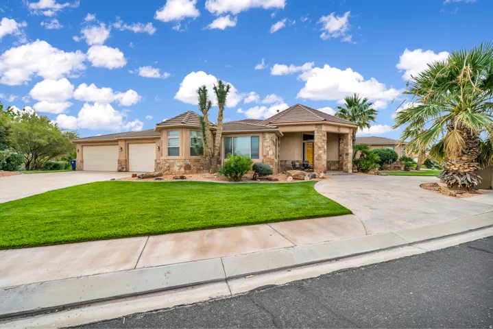 Ranch-style house with stone siding, driveway, a front yard, stucco siding, and a tiled roof