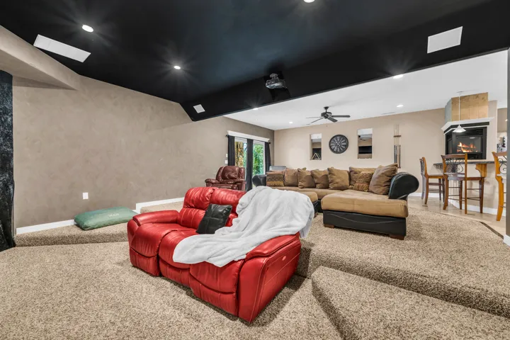Carpeted cinema room with a large fireplace, lofted ceiling, and recessed lighting