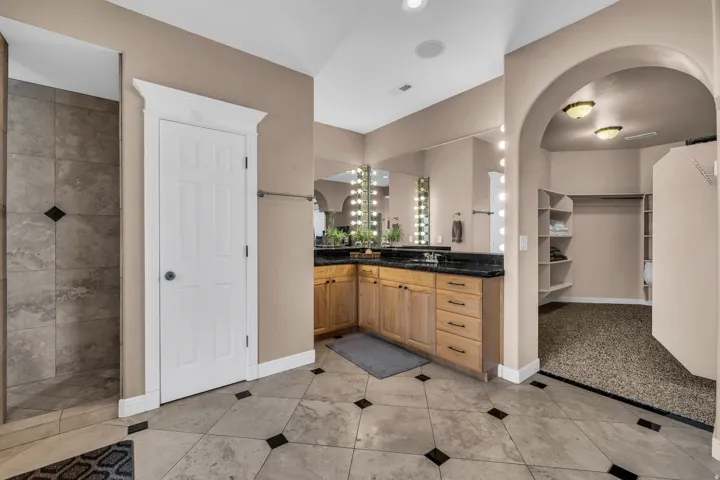 Full bathroom featuring vanity, a spacious closet, and light tile patterned floors