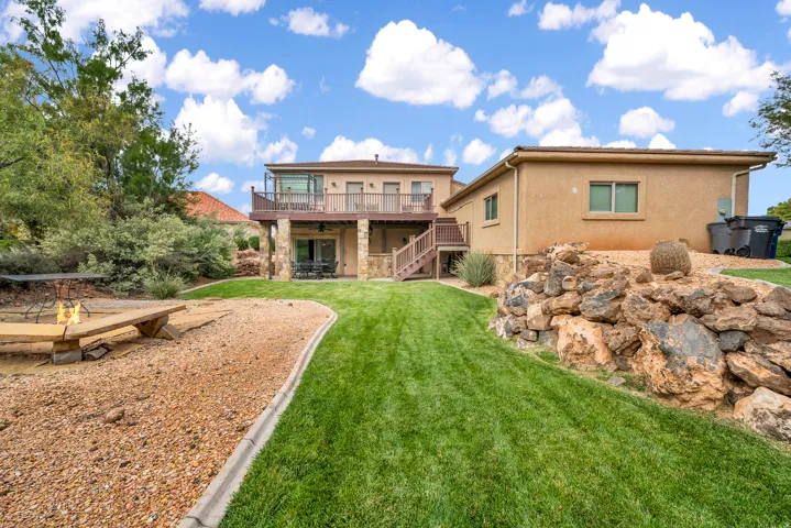 Rear view of property with a deck, a patio, stairway, stucco siding, and a lawn