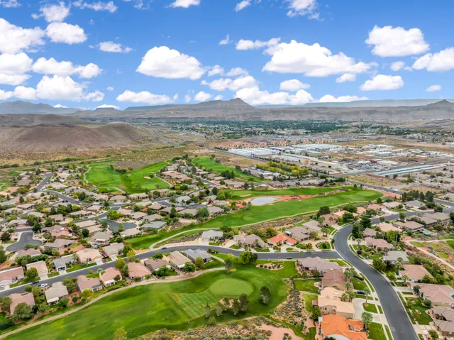 Aerial view of residential area featuring a mountainous background and a golf club