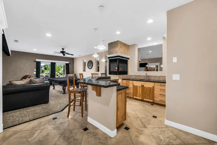 Kitchen featuring a kitchen bar, recessed lighting, open floor plan, hanging light fixtures, and a ceiling fan