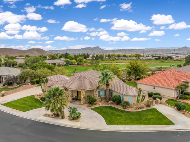 View of front of home with a mountain view, curved driveway, stucco siding, and a front lawn