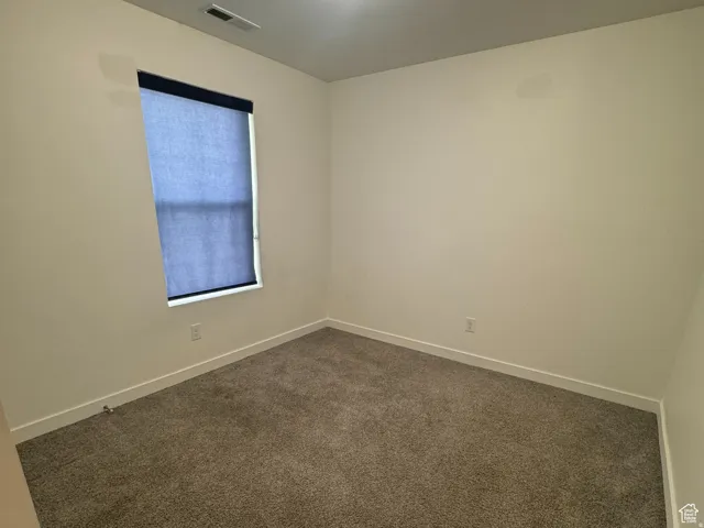Carpeted spare room featuring baseboards
