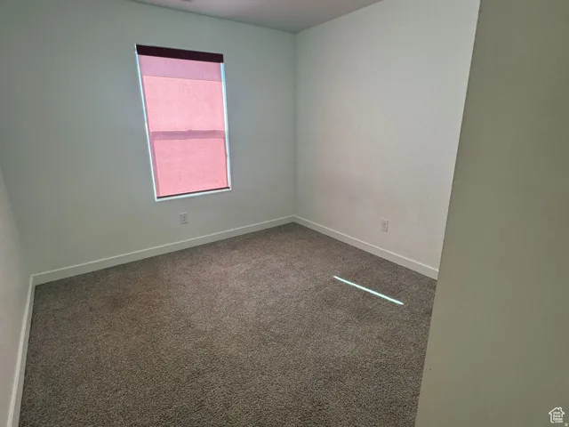 Spare room featuring carpet flooring and baseboards