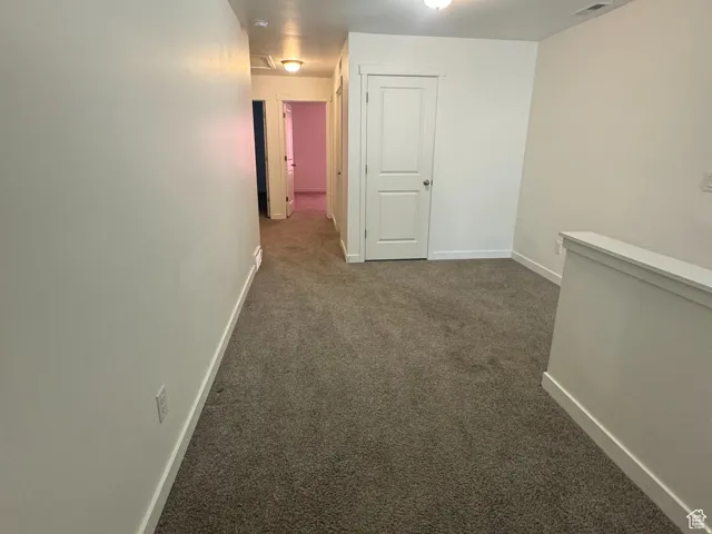 Corridor with dark carpet and baseboards