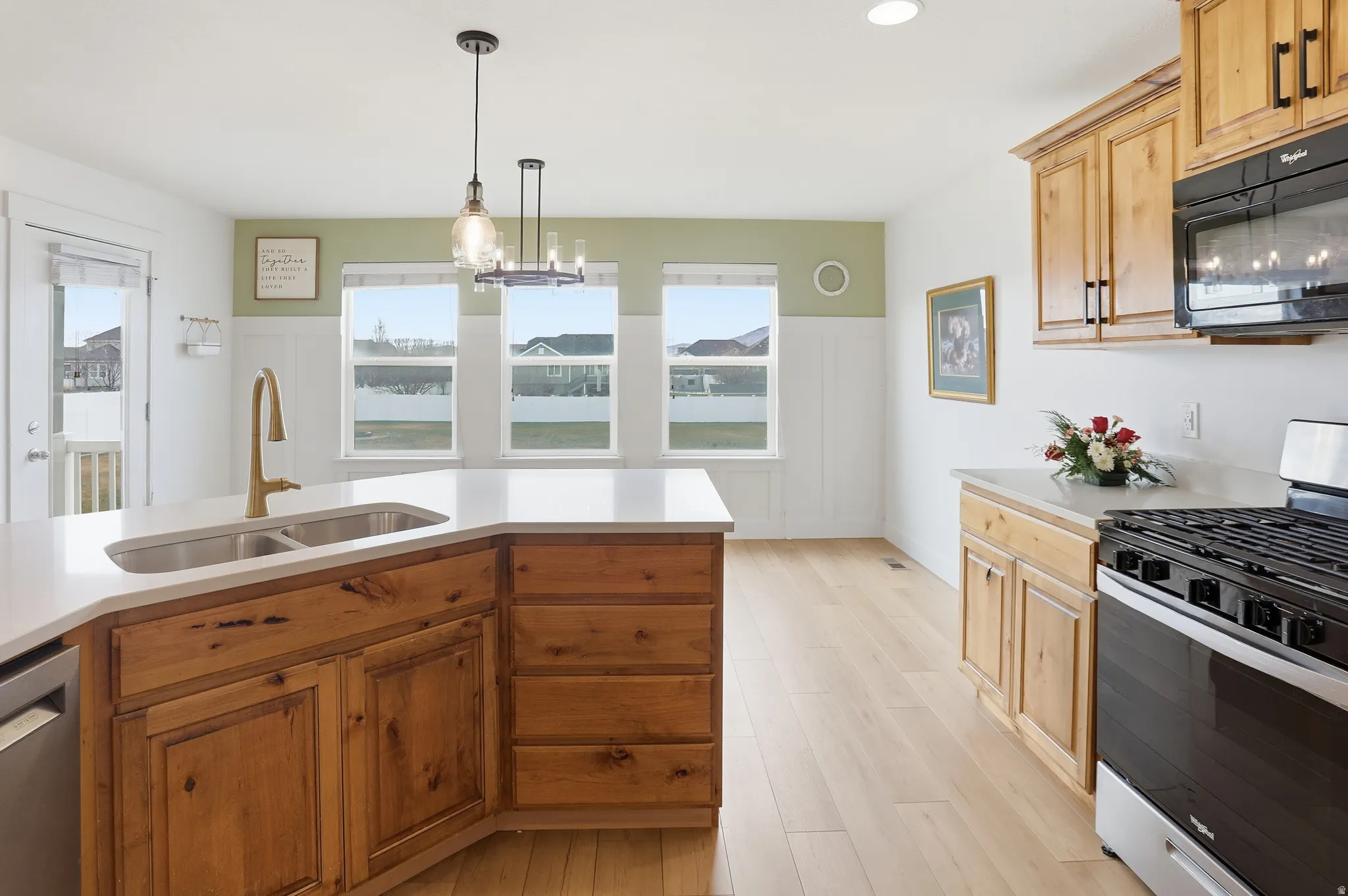 Kitchen featuring stainless steel appliances, pendant lighting, brown cabinetry, and plenty of natural light