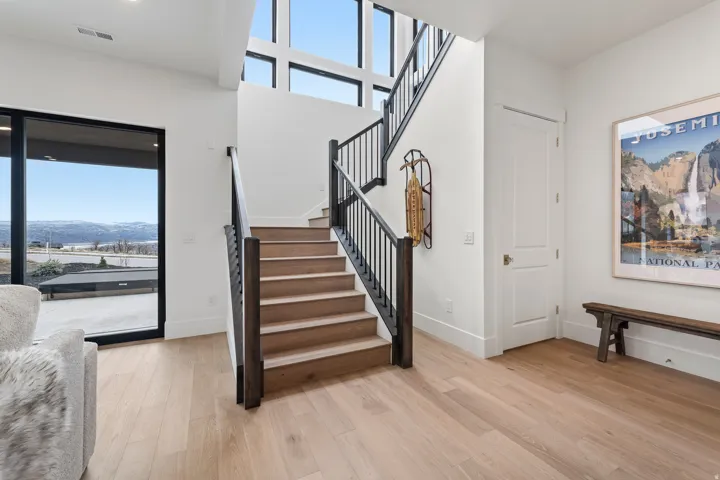 Stairway with healthy amount of natural light, wood finished floors, a high ceiling, and a mountain view