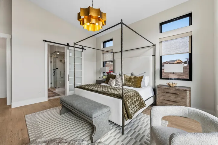 Bedroom with a barn door, wood finished floors, a chandelier, and connected bathroom